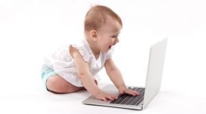 Smiling Baby Looking at Laptop Screen with Hands on Keyboard - Web Design Companies NJ