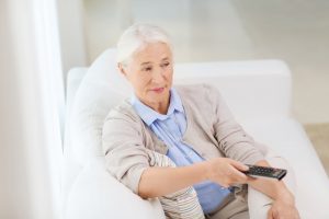 Older woman sitting in a chair with a TV remote
