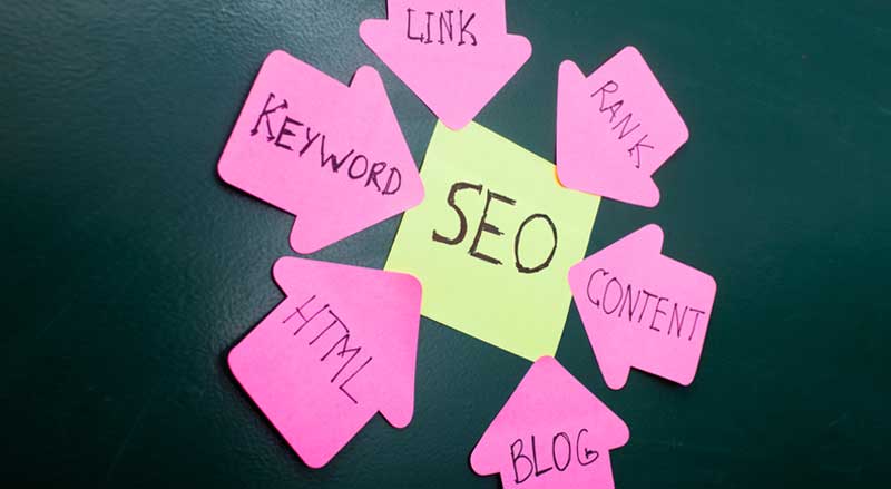 Pink stickers with major components of SEO surrounding and pointing to an SEO sign
