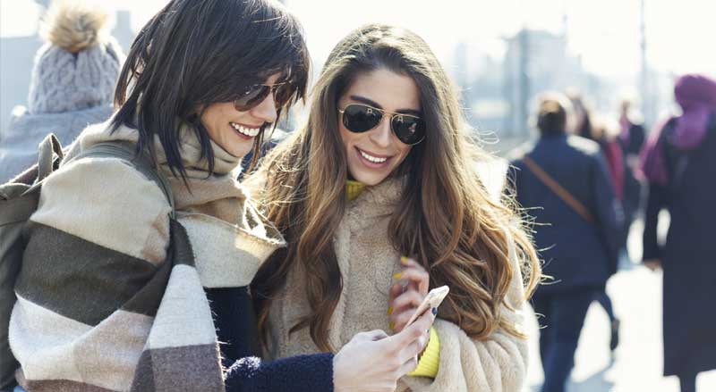 Two women looking at a cell phone outdoors