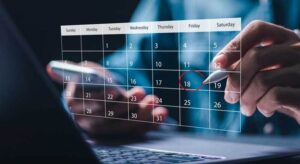Person using a digital pen to mark a date on a virtual calendar overlay displayed above a laptop screen