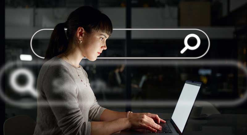Woman searching on laptop with digital search bar overlay representing SEO and online visibility.