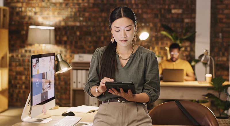 Business owner reviewing digital marketing content and online advertising performance on a tablet in a modern office workspace